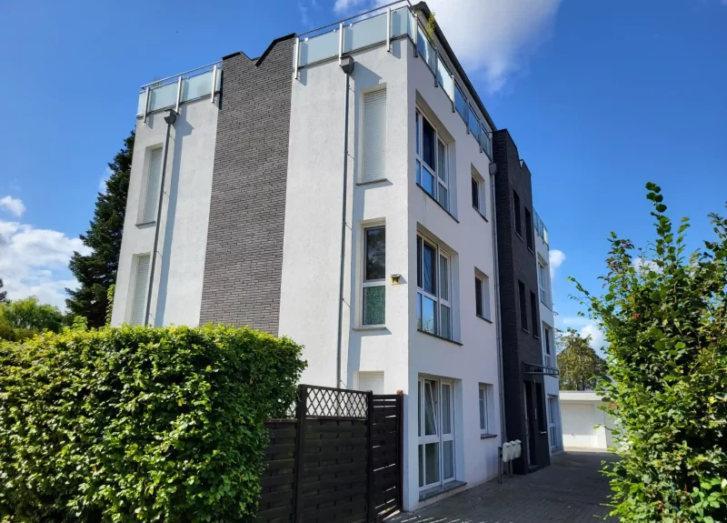 Weißes Mehrfamilienhaus mit einer Verblendung aus Klinkern