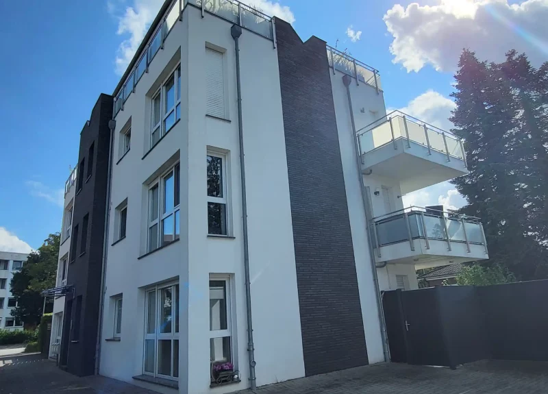 Weißes Mehrfamilienhaus mit einer Verblendung aus Klinkern